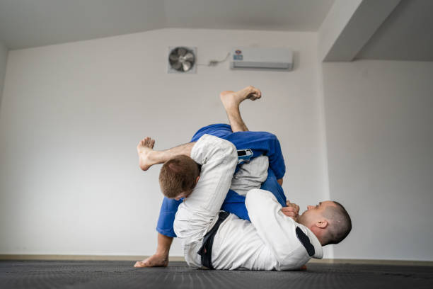 Brazilian jiu jitsu bjj training or sparing two athletes fighters dill martial arts technique at gym on the tatami mats wear kimono gi black belt instructor demonstrate submission armbar juji gatame